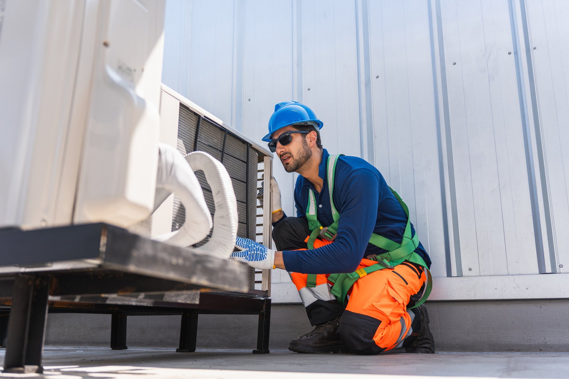 HVAC technician inspecting outdoor air conditioning unit on rooftop
